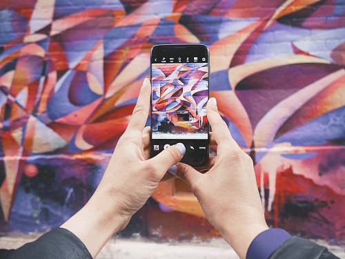 kensington market person holding Android smartphone and taking a photo of abstract wall during daytime toronto